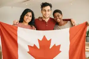 Three smiling people holding a Canadian flag, symbolizing diversity and inclusion supported by immigration translation services in Canada.
