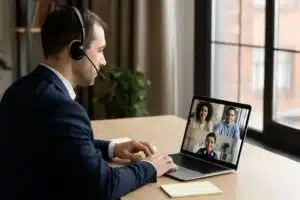 Professional interpreter providing video interpreting service during a virtual meeting on a laptop with diverse participants.