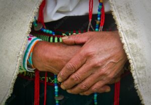 Canadian Indigenous woman in traditional dress with hands together symbolizing cultural preservation and the role of a Canadian Indigenous language translator.
